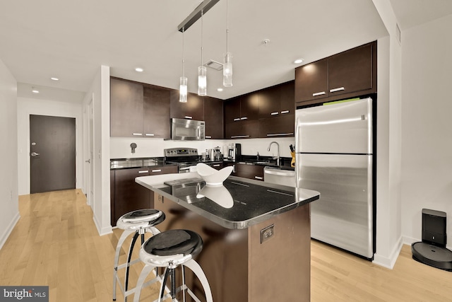1010 Massachusetts Ave NW Unit 706, Washington, DC 20001 - kitchen with stainless steel appliances, light wood-type flooring, dark brown cabinetry, a breakfast bar, and recessed lighting