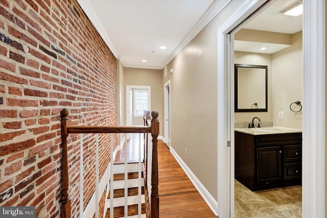 115 N Bradford St, Baltimore, MD 21224 - corridor with crown molding, brick wall, an upstairs landing, light wood-style floors, and recessed lighting