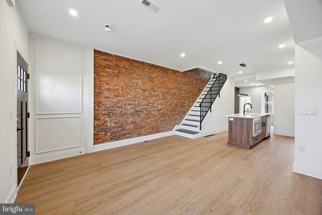 2504 E Cumberland St, Philadelphia, PA 19125 - unfurnished living room featuring light wood finished floors, recessed lighting, brick wall, and stairs
