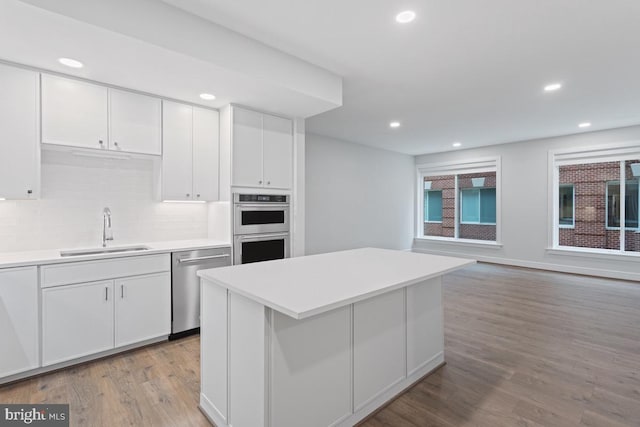635 Slaters Ln Unit 109, Alexandria, VA 22314 - kitchen featuring stainless steel appliances, light wood finished floors, white cabinetry, light countertops, and recessed lighting