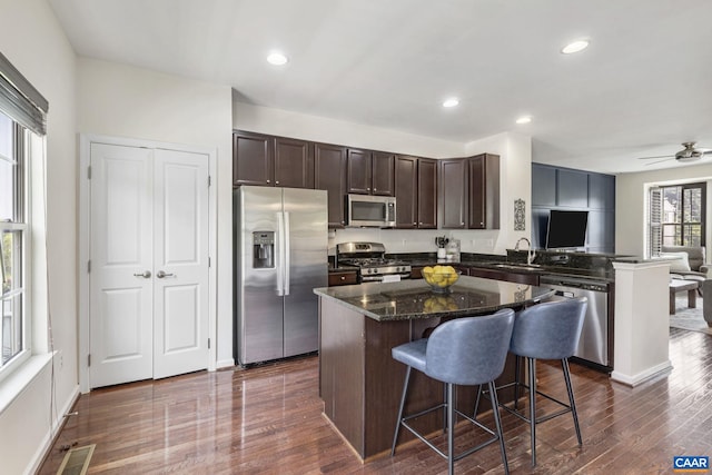 2159 Whispering Hollow Ln, Charlottesville, VA 22911 - kitchen featuring stainless steel appliances, dark brown cabinets, a center island, dark wood-type flooring, and dark stone counters