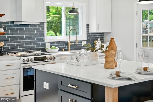 4501 Tipton Ln, Alexandria, VA 22310 - kitchen with stainless steel electric range oven, premium range hood, white cabinets, light countertops, and tasteful backsplash
