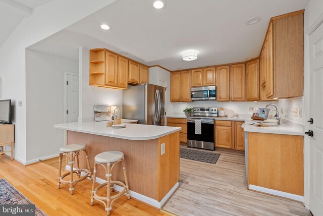 8700 Bluedale St, Alexandria, VA 22308 - kitchen featuring appliances with stainless steel finishes, a peninsula, open shelves, light wood-style flooring, and a kitchen bar