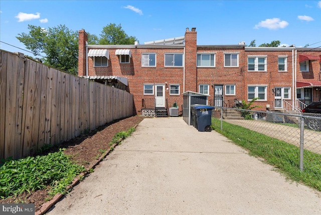 307 19th St NE, Washington, DC 20002 - rear view of house with a chimney, brick siding, and concrete driveway