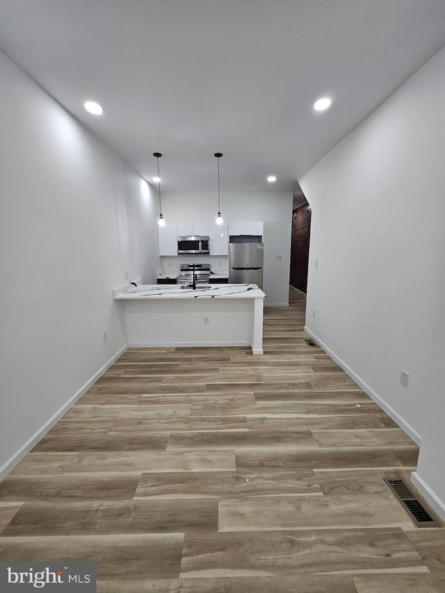 3239 N 13th St, Philadelphia, PA 19140 - kitchen with appliances with stainless steel finishes, a peninsula, light wood-style flooring, recessed lighting, and white cabinets