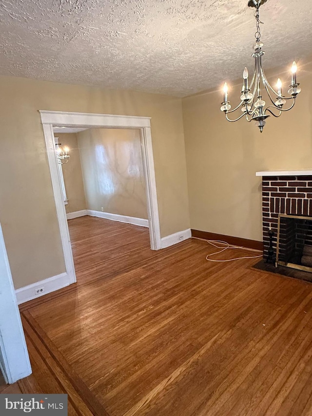 1812 E 32nd St, Baltimore, MD 21218 - unfurnished dining area with a chandelier, wood finished floors, a textured ceiling, and a brick fireplace