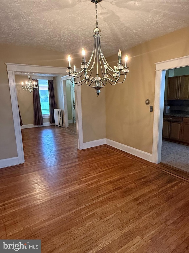 1812 E 32nd St, Baltimore, MD 21218 - unfurnished dining area featuring a chandelier, radiator, wood finished floors, and a textured ceiling