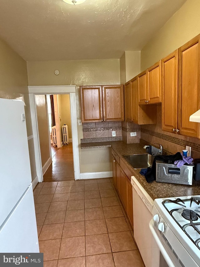 1812 E 32nd St, Baltimore, MD 21218 - kitchen featuring white appliances, radiator heating unit, light tile patterned flooring, tasteful backsplash, and dark countertops