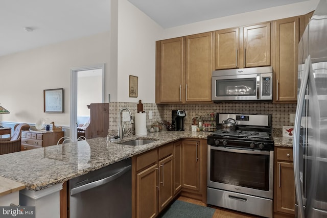 7330 Maple Ave Unit 116, Pennsauken, NJ 08109 - kitchen with stainless steel appliances, a peninsula, backsplash, light stone counters, and brown cabinetry