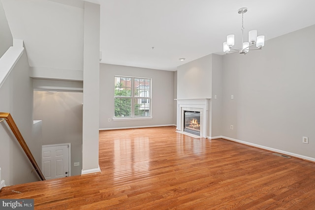 12119 Amber Ridge Cir, Germantown, MD 20876 - unfurnished living room featuring wood finished floors, a chandelier, and a fireplace with flush hearth