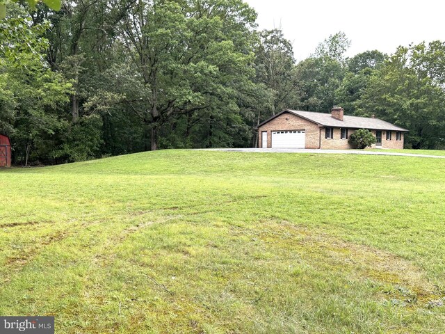 16611 Summers Ln, Brandywine, MD 20613 - view of green lawn with a garage and a forest view