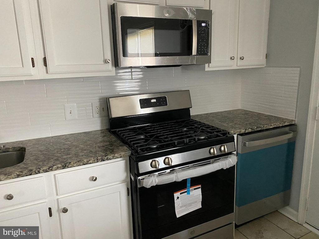 4214 Labyrinth Rd, Baltimore, MD 21215 - kitchen with appliances with stainless steel finishes, white cabinets, backsplash, and dark stone countertops