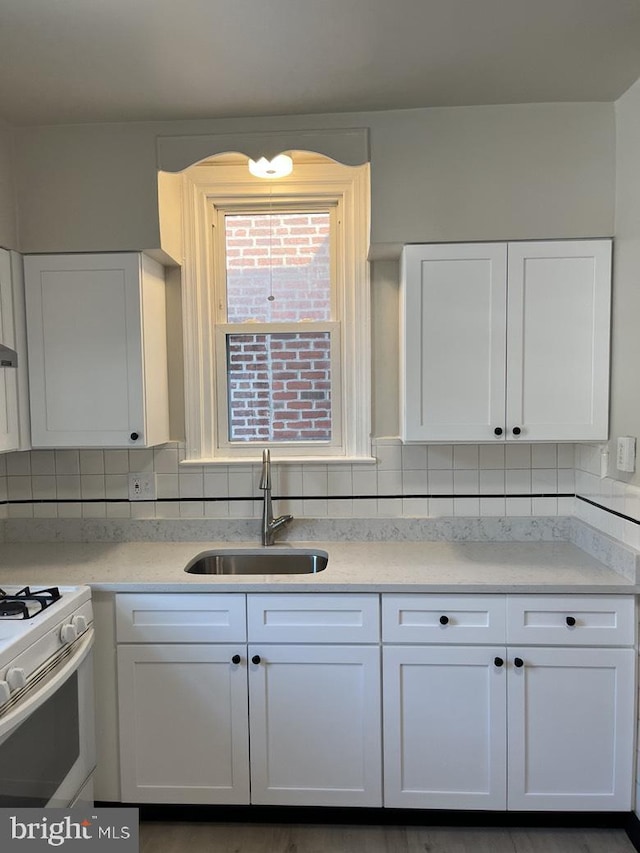3019 Magee Ave, Philadelphia, PA 19149 - kitchen with white gas stove, white cabinetry, light countertops, and decorative backsplash