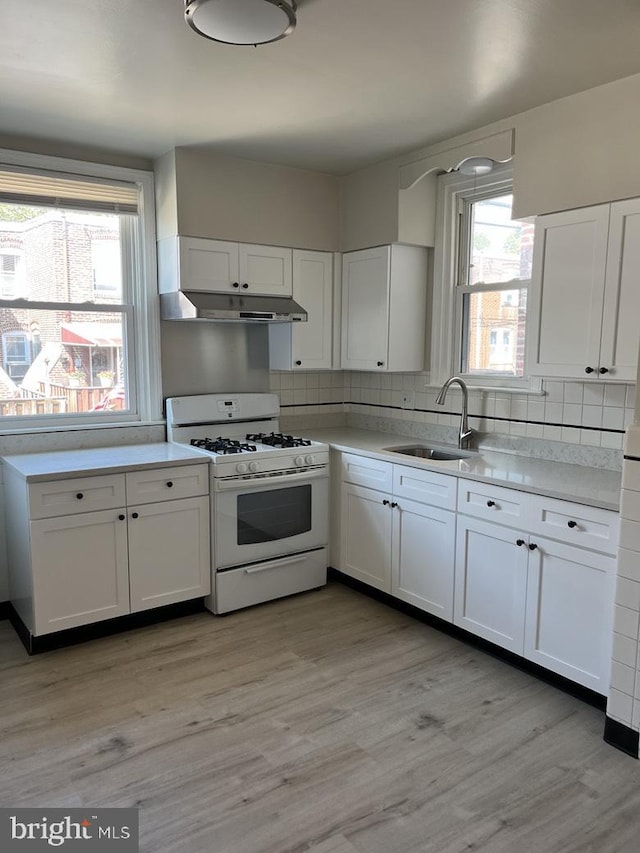3019 Magee Ave, Philadelphia, PA 19149 - kitchen featuring gas range gas stove, under cabinet range hood, white cabinets, light countertops, and tasteful backsplash