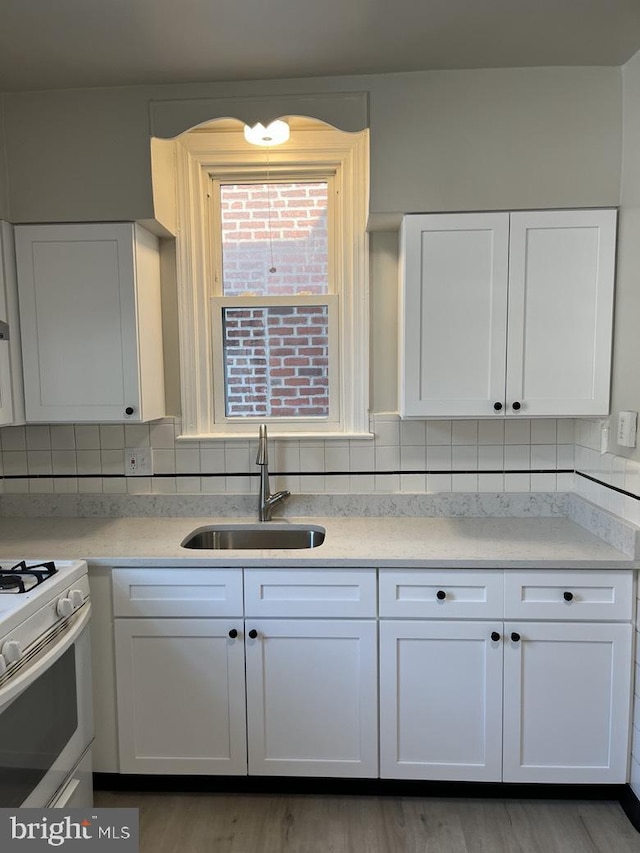 3019 Magee Ave, Philadelphia, PA 19149 - kitchen featuring white gas stove, white cabinetry, light countertops, backsplash, and light wood-type flooring