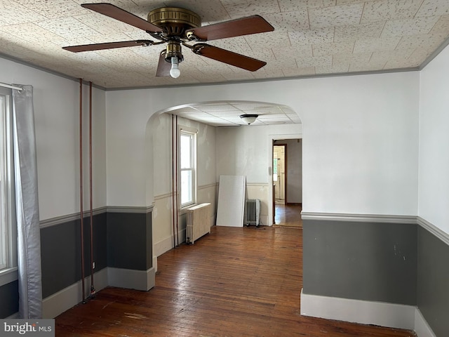 135-137 S 6th St, Shamokin, PA 17872 - spare room featuring arched walkways, radiator heating unit, ceiling fan, and hardwood / wood-style floors