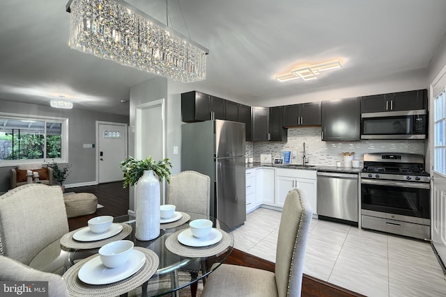 267 Southeastern Ter, Baltimore, MD 21221 - kitchen featuring appliances with stainless steel finishes, backsplash, open floor plan, light tile patterned floors, and stone countertops