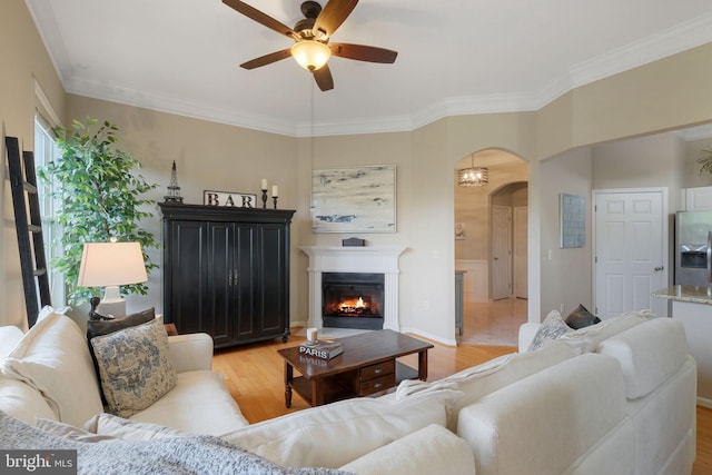7 Booth St Unit 402, Gaithersburg, MD 20878 - living room with ceiling fan, arched walkways, light wood-style floors, crown molding, and a warm lit fireplace