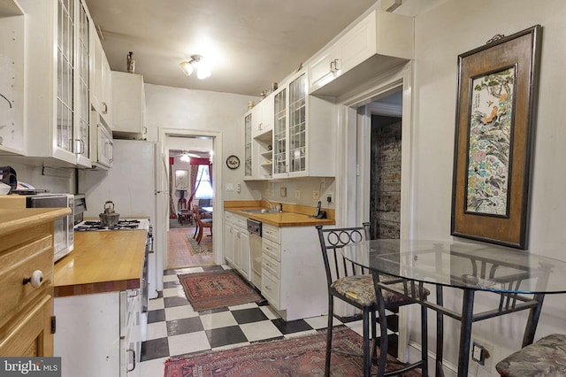 1117 S Carolina Ave SE, Washington, DC 20003 - kitchen featuring butcher block countertops, dark flooring, white cabinetry, white appliances, and glass insert cabinets