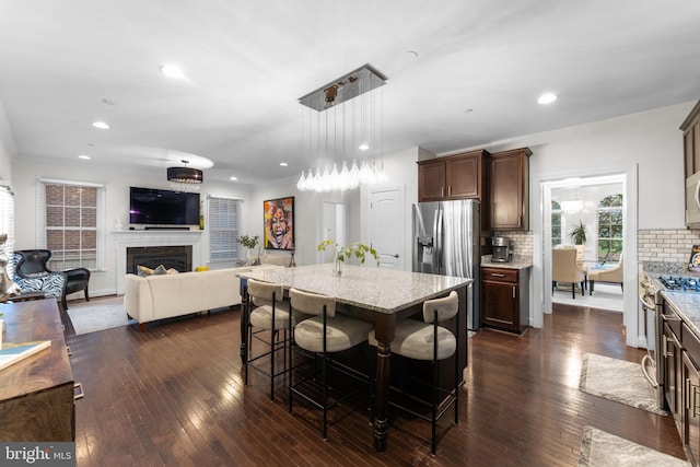 6006 New Hampshire Ave NE, Washington, DC 20011 - kitchen featuring appliances with stainless steel finishes, light stone counters, backsplash, dark brown cabinets, and a breakfast bar area