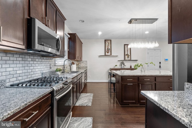6006 New Hampshire Ave NE, Washington, DC 20011 - kitchen featuring appliances with stainless steel finishes, a center island, dark brown cabinetry, light stone counters, and recessed lighting