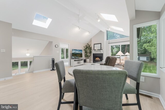 7920 Old Falls Rd, Mclean, VA 22102 - dining area featuring a skylight, lofted ceiling, track lighting, a lit fireplace, and ceiling fan