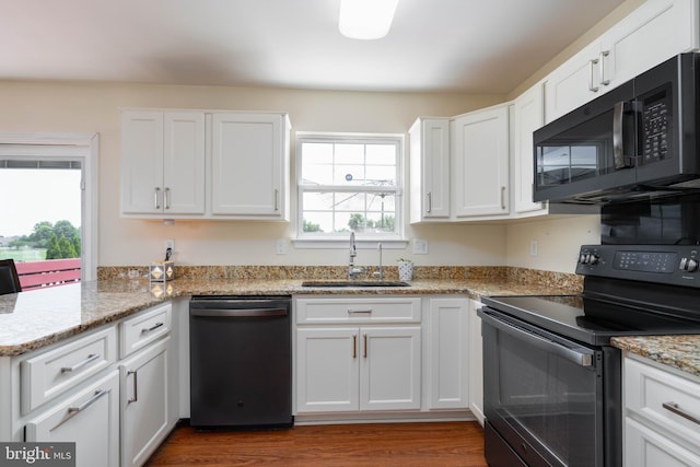 715 Dairy Dr, Middletown, DE 19709 - kitchen with black appliances, white cabinetry, wood finished floors, light stone countertops, and a peninsula