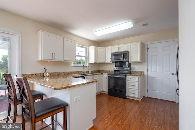 715 Dairy Dr, Middletown, DE 19709 - kitchen featuring stainless steel microwave, black electric range oven, a peninsula, white cabinetry, and a breakfast bar area