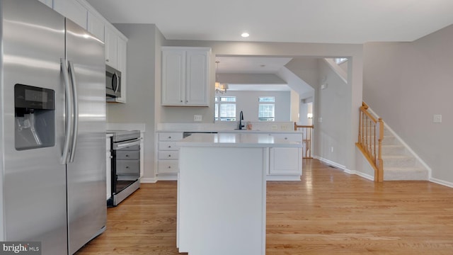 4724 Hanrahan Pl, Alexandria, VA 22309 - kitchen featuring appliances with stainless steel finishes, a center island, white cabinetry, light countertops, and light wood-style floors