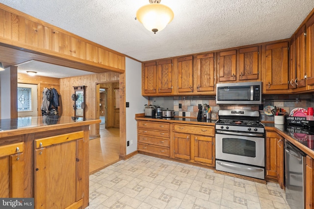 590 Vaught Dr, Front Royal, VA 22630 - kitchen with appliances with stainless steel finishes, brown cabinetry, brick patterned floors, tasteful backsplash, and a textured ceiling