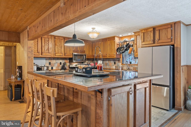 590 Vaught Dr, Front Royal, VA 22630 - kitchen featuring stainless steel appliances, light wood-type flooring, backsplash, brown cabinets, and wooden walls