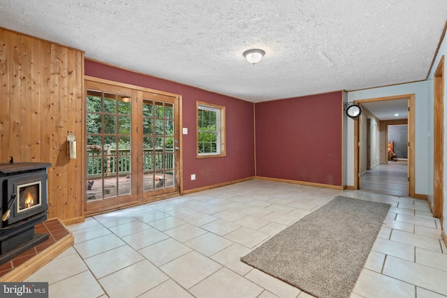 590 Vaught Dr, Front Royal, VA 22630 - unfurnished living room featuring a wood stove, tile patterned floors, wooden walls, and a textured ceiling