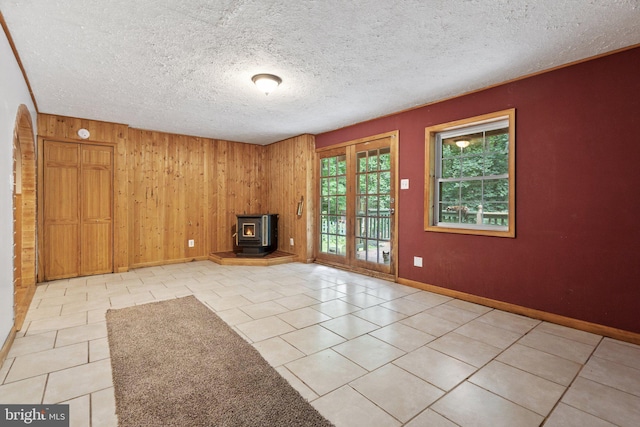 590 Vaught Dr, Front Royal, VA 22630 - unfurnished living room featuring a wood stove, wooden walls, light tile patterned floors, and a textured ceiling