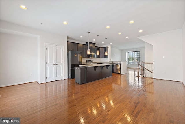 19503 Vaughn Landing Dr, Germantown, MD 20874 - kitchen with stainless steel appliances, a kitchen island, a kitchen bar, wood-type flooring, and recessed lighting