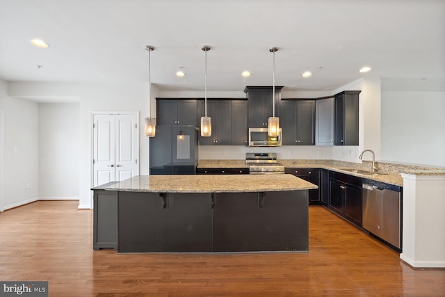 19503 Vaughn Landing Dr, Germantown, MD 20874 - kitchen featuring appliances with stainless steel finishes, a kitchen island, light stone countertops, and recessed lighting