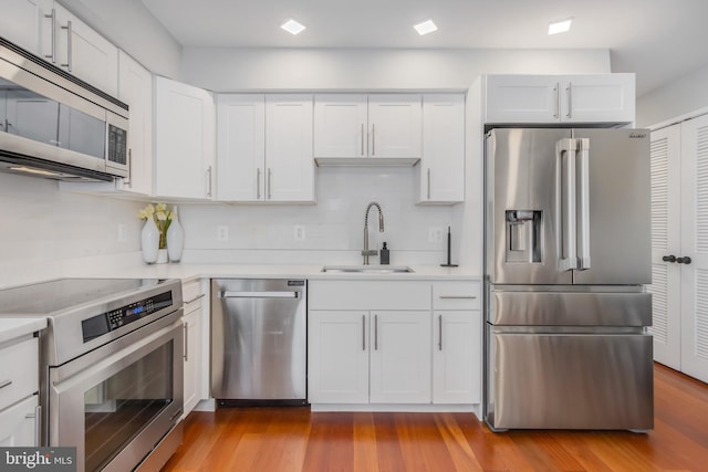 4106 Gault Pl NE Unit 3, Washington, DC 20019 - kitchen featuring stainless steel appliances, light countertops, white cabinets, wood finished floors, and decorative backsplash