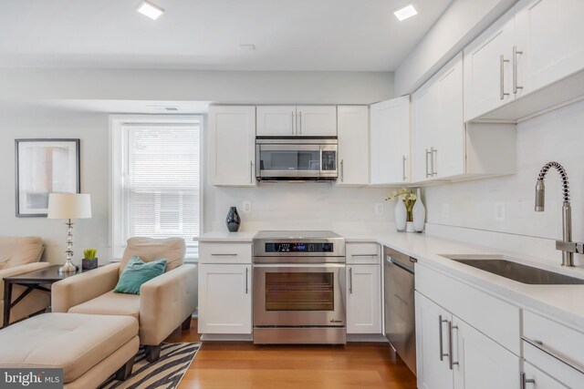 4106 Gault Pl NE Unit 3, Washington, DC 20019 - kitchen featuring appliances with stainless steel finishes, white cabinets, light wood-type flooring, light countertops, and open floor plan
