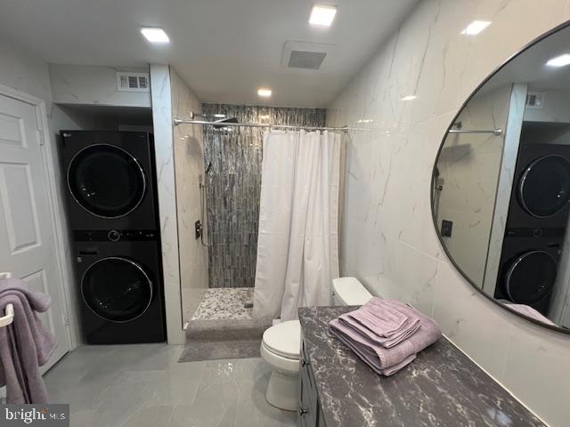 12163 Penderview Ter Unit 1034, Fairfax, VA 22033 - bathroom with stacked washer / dryer, a tile shower, vanity, and marble finish flooring