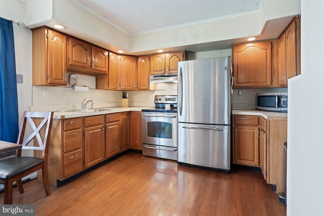 25 Tulip Ln, Levittown, PA 19054 - kitchen featuring stainless steel appliances, under cabinet range hood, light countertops, a textured ceiling, and brown cabinetry