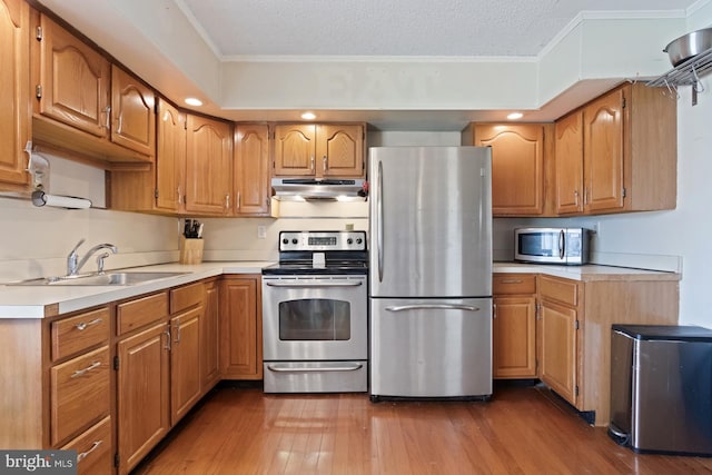 25 Tulip Ln, Levittown, PA 19054 - kitchen featuring appliances with stainless steel finishes, wood finished floors, ornamental molding, under cabinet range hood, and light countertops