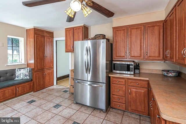 722 River Rd, Ewing, NJ 08628 - kitchen with stainless steel appliances, brown cabinetry, a ceiling fan, and light tile patterned floors