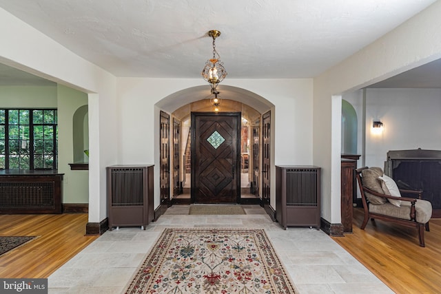 722 River Rd, Ewing, NJ 08628 - entrance foyer featuring arched walkways, radiator heating unit, and light wood finished floors