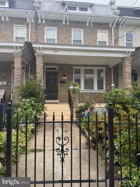 812 Emerson St NW, Washington, DC 20011 - view of front of property featuring brick siding, mansard roof, a porch, and a fenced front yard