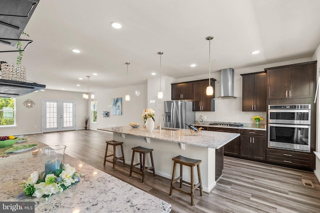 20318 Peacemaker Dr, Germantown, MD 20874 - kitchen featuring wall chimney exhaust hood, stainless steel appliances, light wood finished floors, dark brown cabinetry, and recessed lighting