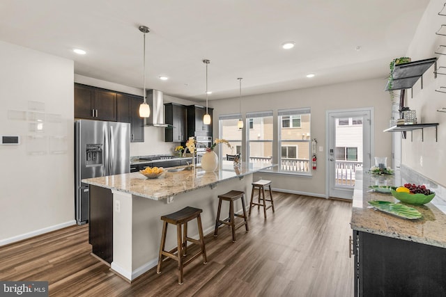 20318 Peacemaker Dr, Germantown, MD 20874 - kitchen featuring wall chimney range hood, appliances with stainless steel finishes, dark wood-style flooring, a kitchen breakfast bar, and an island with sink