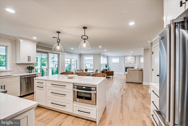 569 Riverside Dr, Princeton, NJ 08540 - kitchen with stainless steel appliances, crown molding, light countertops, light wood-style flooring, and decorative light fixtures