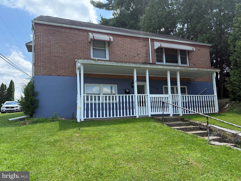 2230 Mckinley Ave, Reading, PA 19609 - view of front of house with brick siding, a front yard, and covered porch