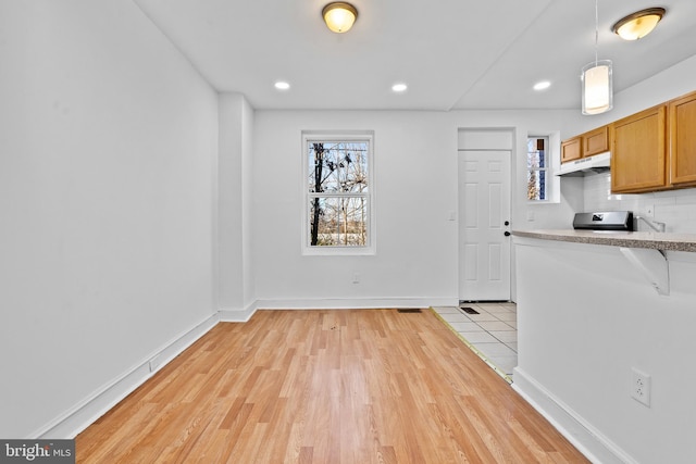 3402 Elmley Ave, Baltimore, MD 21213 - kitchen with under cabinet range hood, plenty of natural light, light wood-type flooring, a breakfast bar area, and recessed lighting