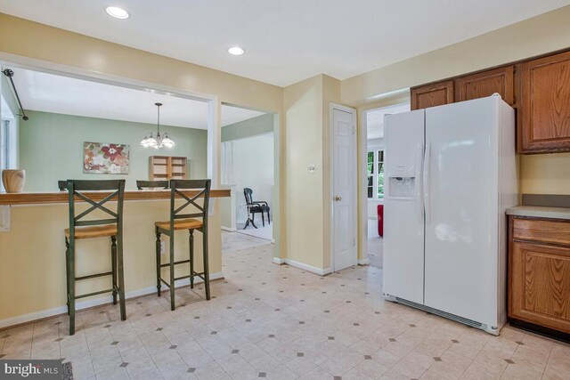 3077 Eutaw Forest Dr, Waldorf, MD 20603 - kitchen with white refrigerator with ice dispenser, brown cabinetry, a kitchen breakfast bar, a chandelier, and recessed lighting