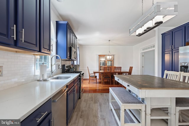 3960 Mountain View Ave, Easton, PA 18045 - kitchen with blue cabinetry, appliances with stainless steel finishes, backsplash, light wood-type flooring, and hanging light fixtures